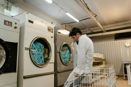 a photo of a man waiting for a laundry machine.